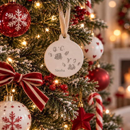 Personalised pet paw print Christmas decoration with Simba text hanging on a Christmas tree